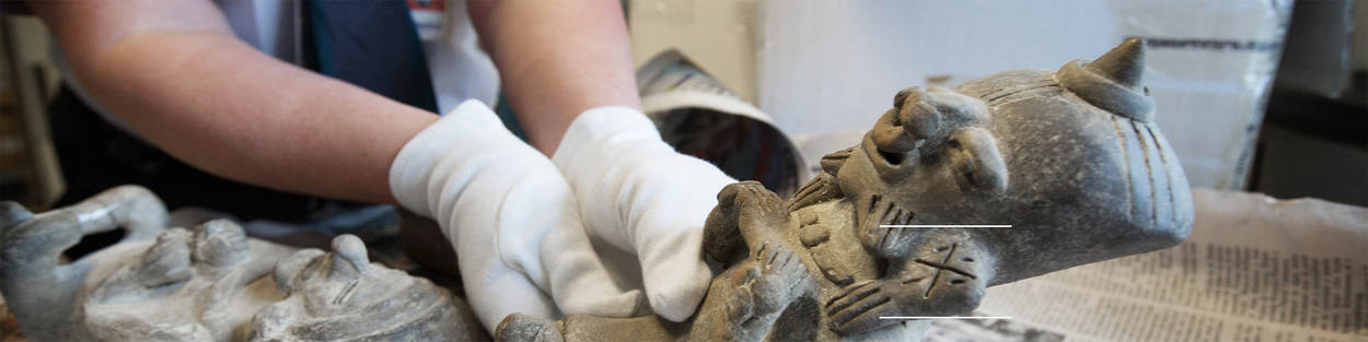 Decoratieve banner van een douanebeambte die met handschoenen een etnografisch beeld vast heeft