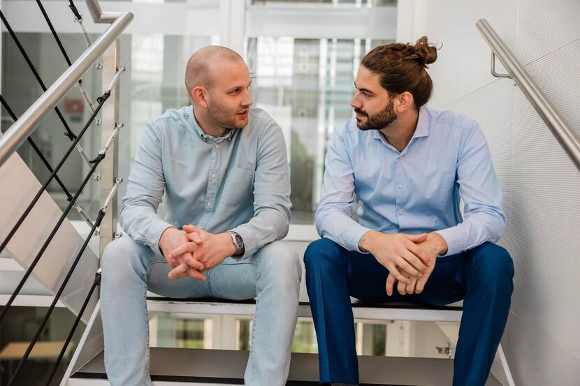 Twee medewerkers van de Inspectie in gesprek in het trappenhuis