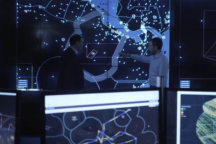 Maritime Observatory. Twee personen staan voor een scherm met data in beeld. Vooraan staan andere schermen die data tonen.